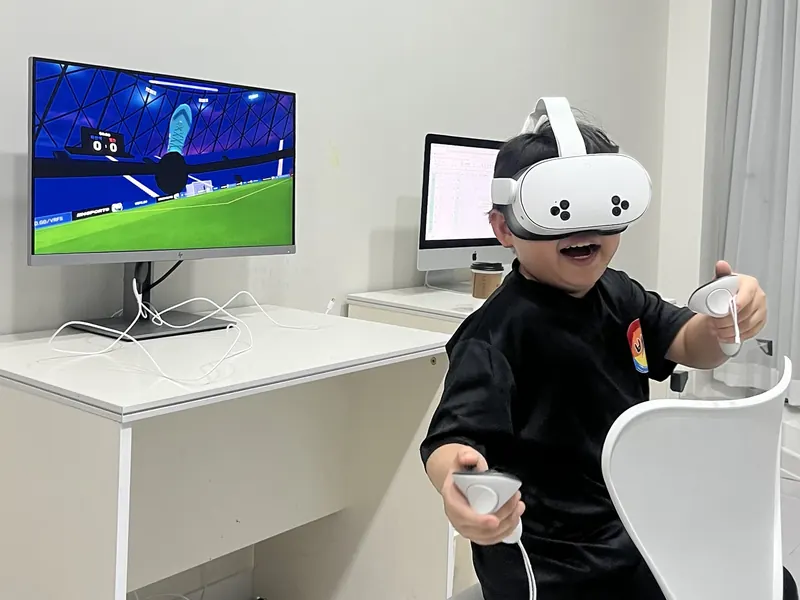 VR 헤드셋을 쓰고 가상 축구를 즐기며 웃는 아이